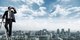 A man in a suit standing on a ladder with binoculars looking over the top of a city under a sunny sky with wispy clouds [Image by creator Kurhan from AdobeStock]